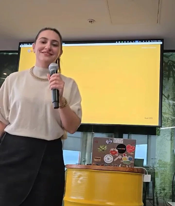 With a microphone by a yellow screen, a frame of her talk