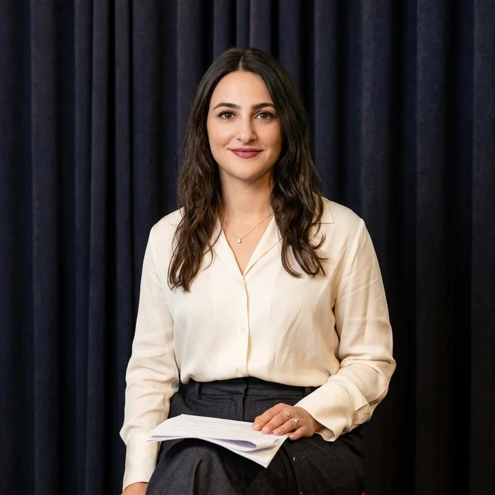 Seated on a panel, a calm smile