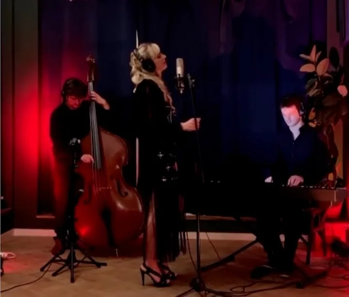 Oli Gosh singing with a double bass and a piano, in red and blue light